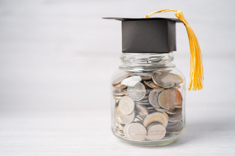 A graduation cap sitting on a jar of quarters.